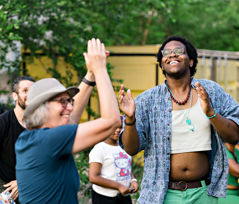 Happy community crowd claps and dances outside