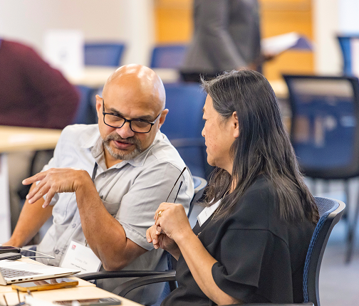 Male founder at table in conversation with female founder