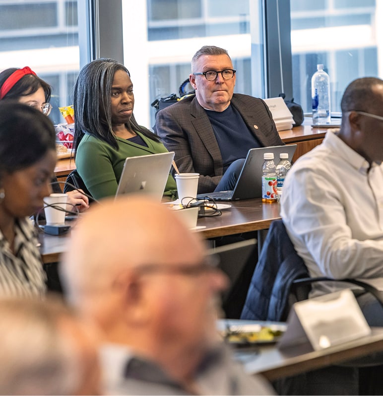 Professional man and professional woman look on from table