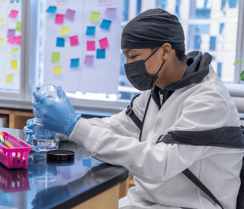 Male student measures out liquid in laboratory setting